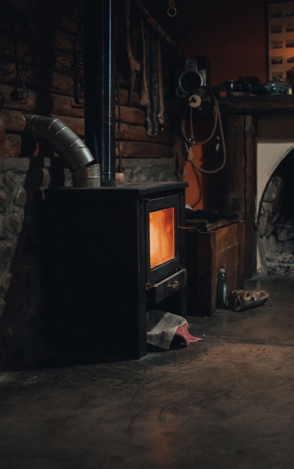 Poêle à bois en fonction dans un séjour aux murs de pierre